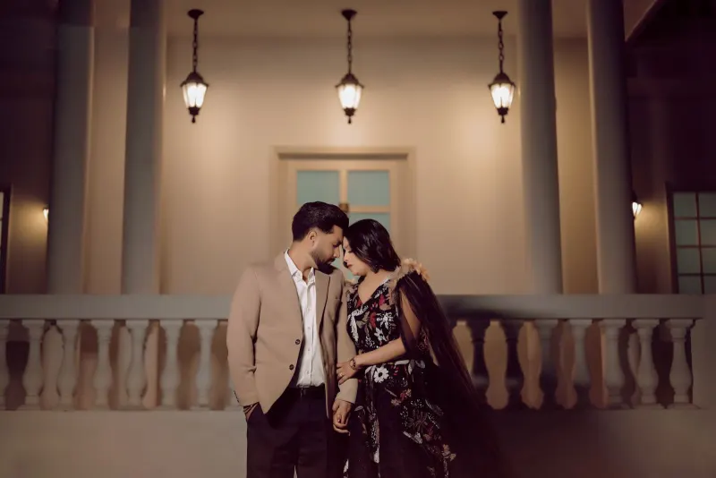 Couple touching foreheads on a lamplit colonial balcony at night, in cinematic warm tones