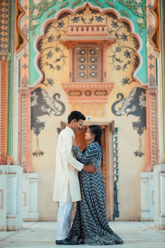 Couple embracing beneath an ornately painted archway with elephant murals in Jaipur