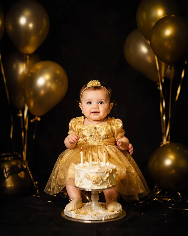 First birthday setup with gold balloons and a cake